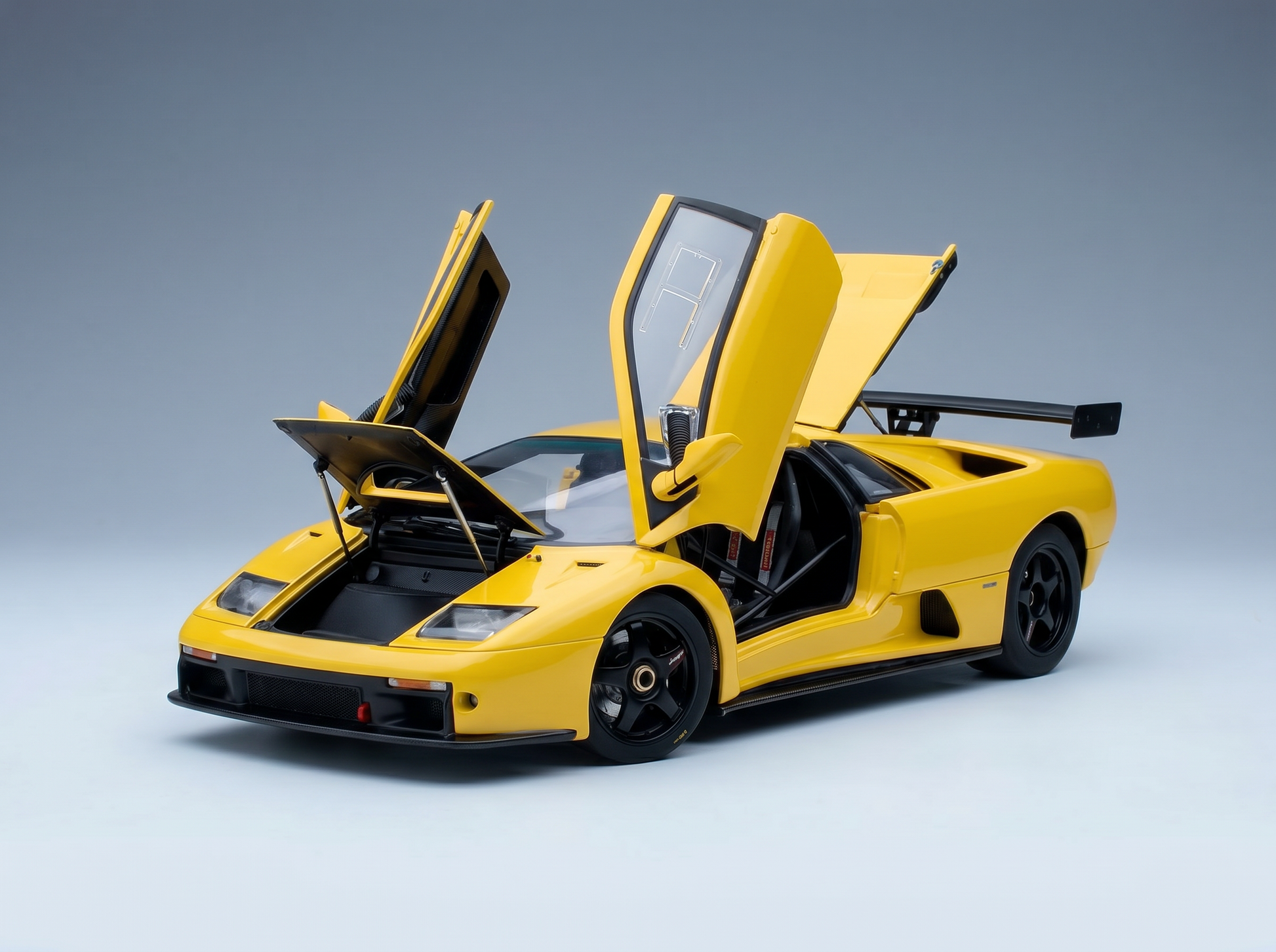 Yellow scale model car with open doors, showcased by Vroomi for collectors and motorsport fans.