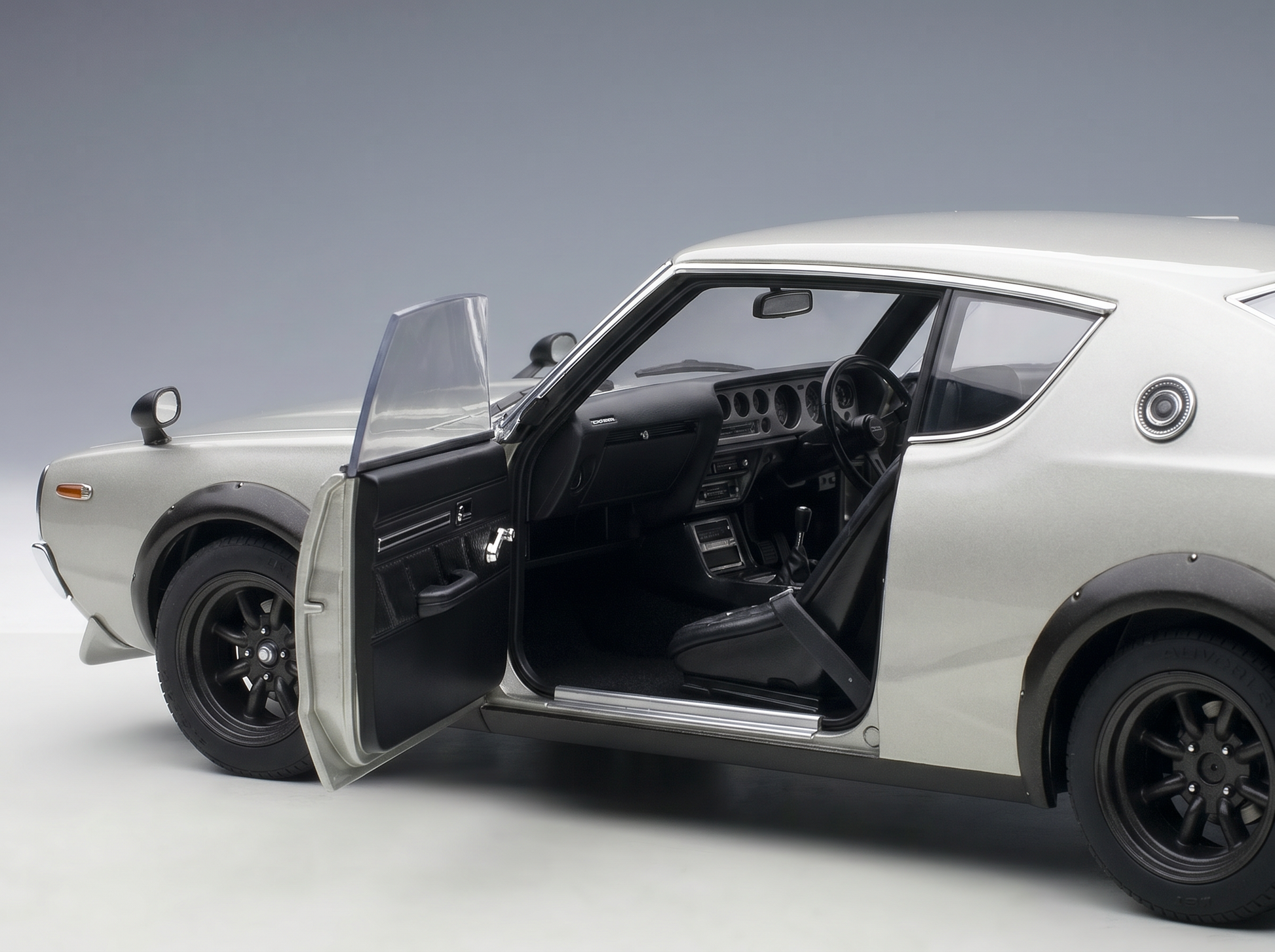 Silbernes Modellauto mit geöffneten Türen, detailgetreuem Innenraum und „Vroomi“-Logo für Sammler.