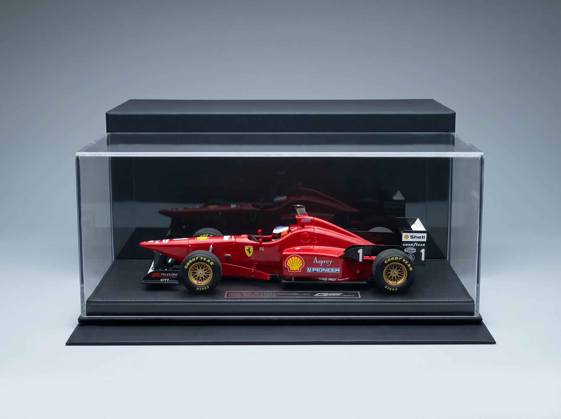 Red Ferrari F1 scale model car in display case, featuring Shell and Goodyear logos, showcased by Vroomi