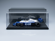 Blau-weißes Modellauto im Maßstab 1:18 mit „Elf“- und „Goodyear“-Logo, ausgestellt in einer durchsichtigen Vitrine bei Vroomi