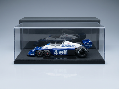 Blau-weißes Modellauto im Maßstab 1:18 mit „Elf“- und „Goodyear“-Logo, ausgestellt in einer durchsichtigen Vitrine bei Vroomi