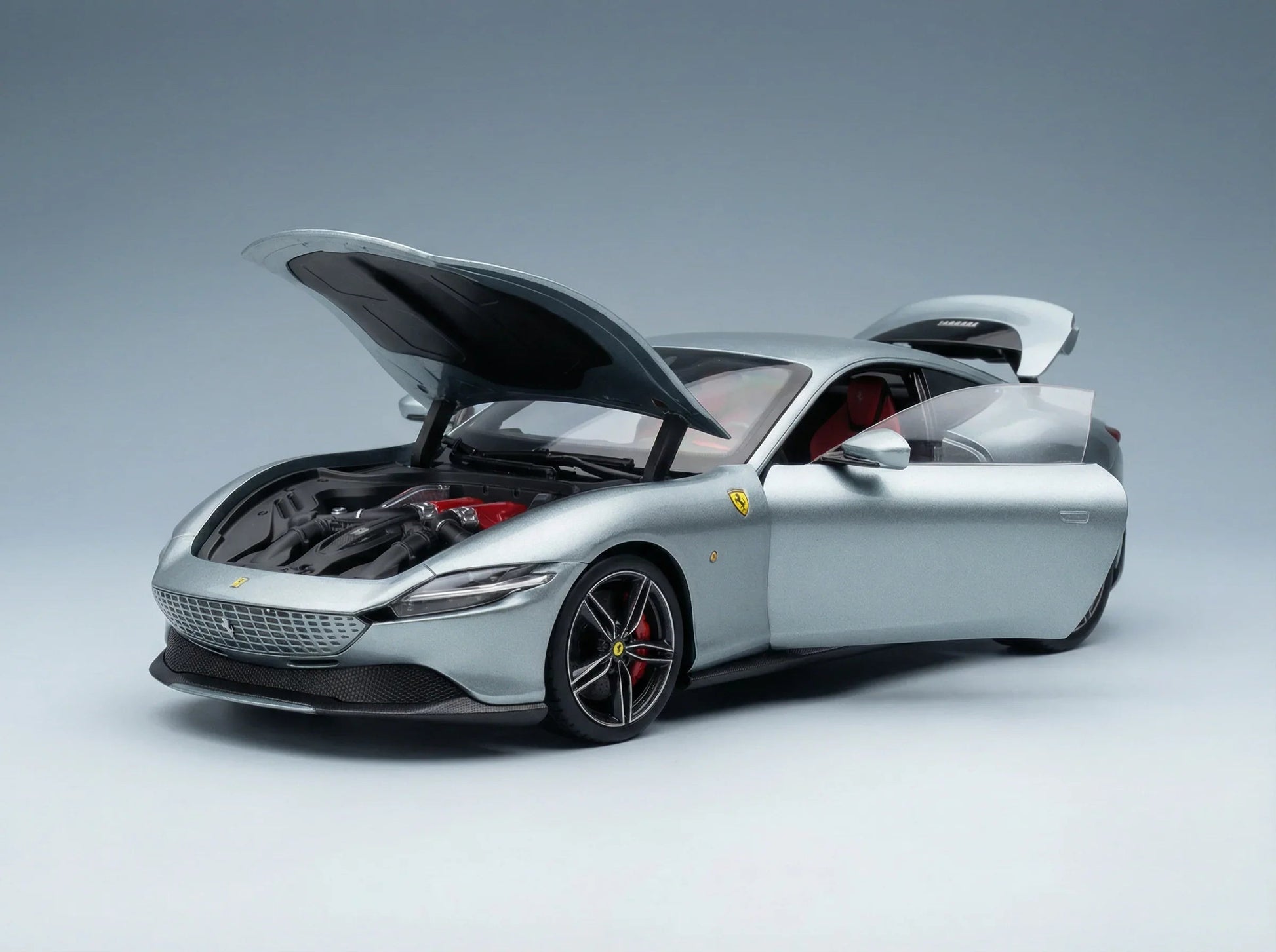 Maqueta de un Ferrari plateado con el capó y las puertas abiertos, motor detallado e interior rojo, en Vroomi