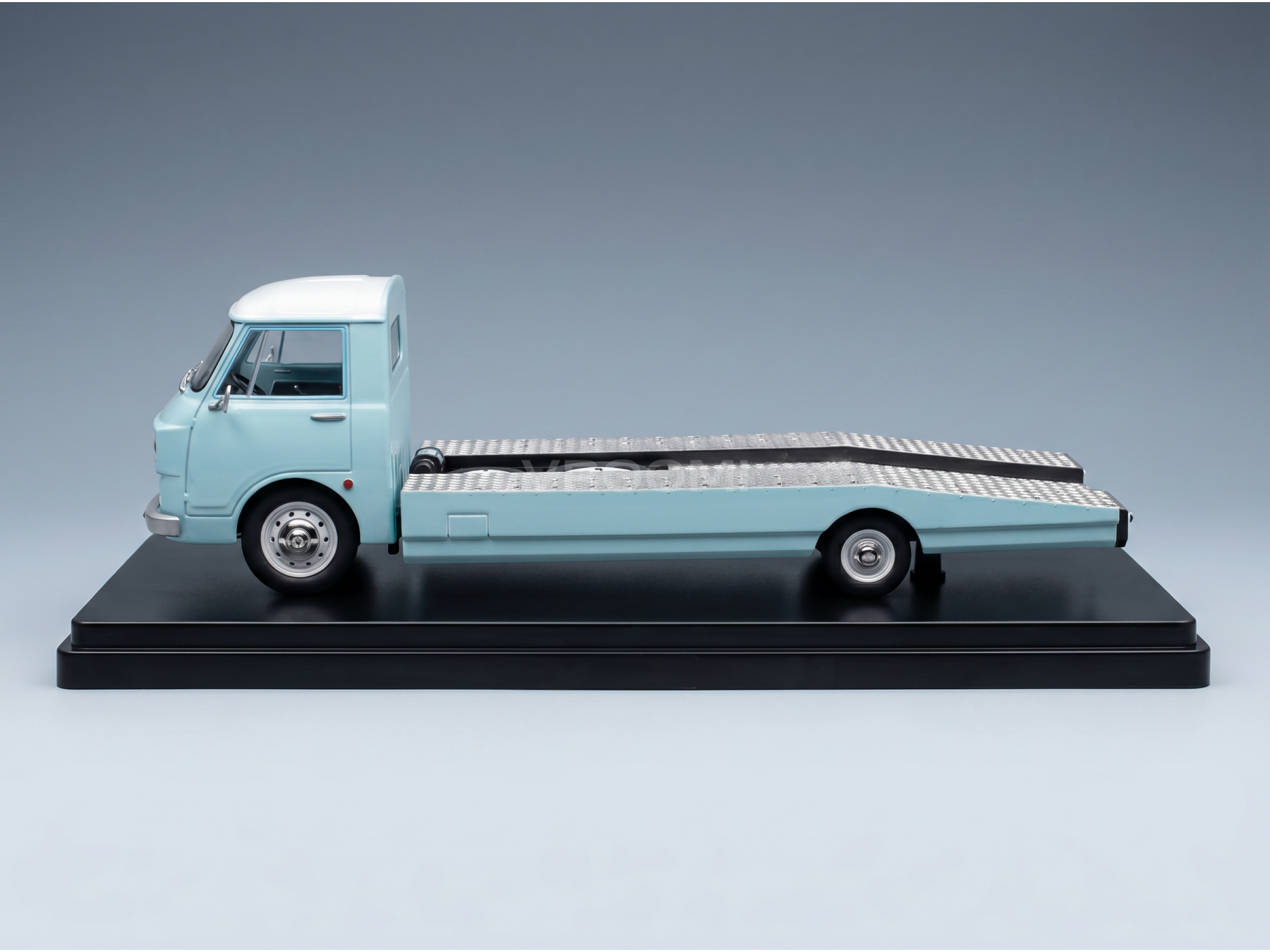Camión transportador de coches a escala, de color azul claro, de la marca Vroomi; réplica detallada de fundición a presión sobre una base negra