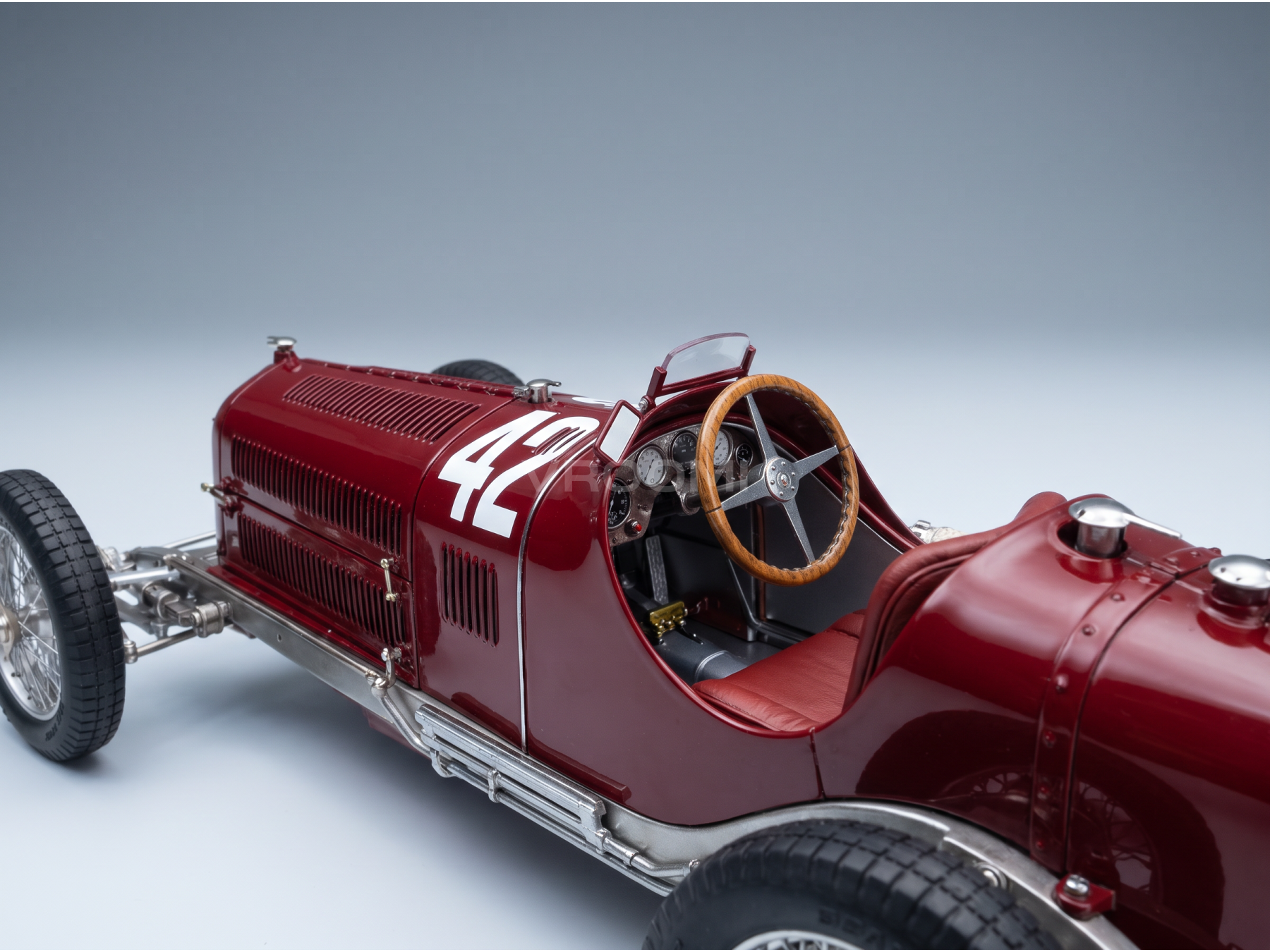 Gros plan sur une maquette vintage de voiture de course rouge portant le numéro 42, mettant l'accent sur le cockpit.