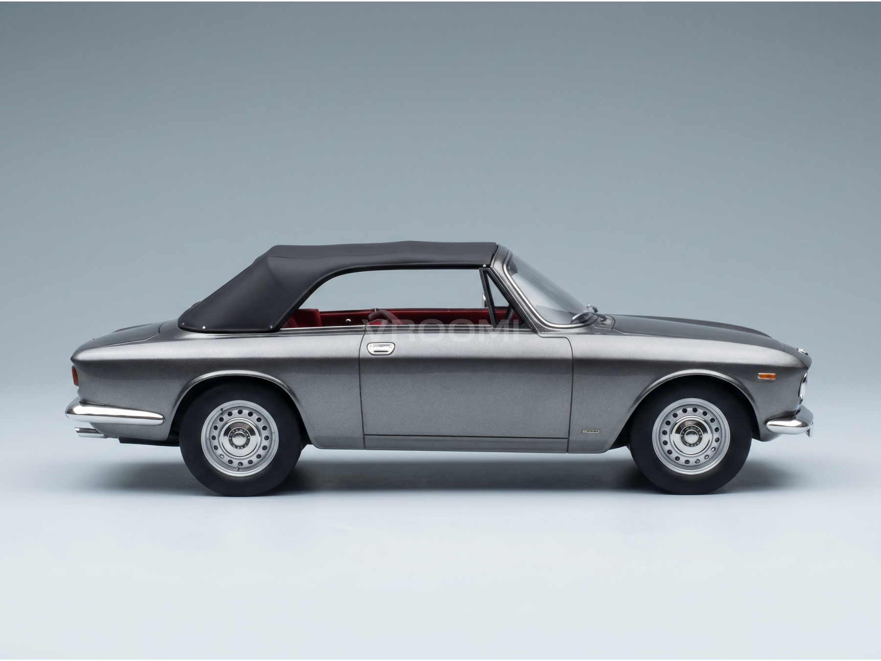 Zilverkleurig cabriolet-schaalmodel met zwarte kap en rood interieur, gepresenteerd door Vroomi