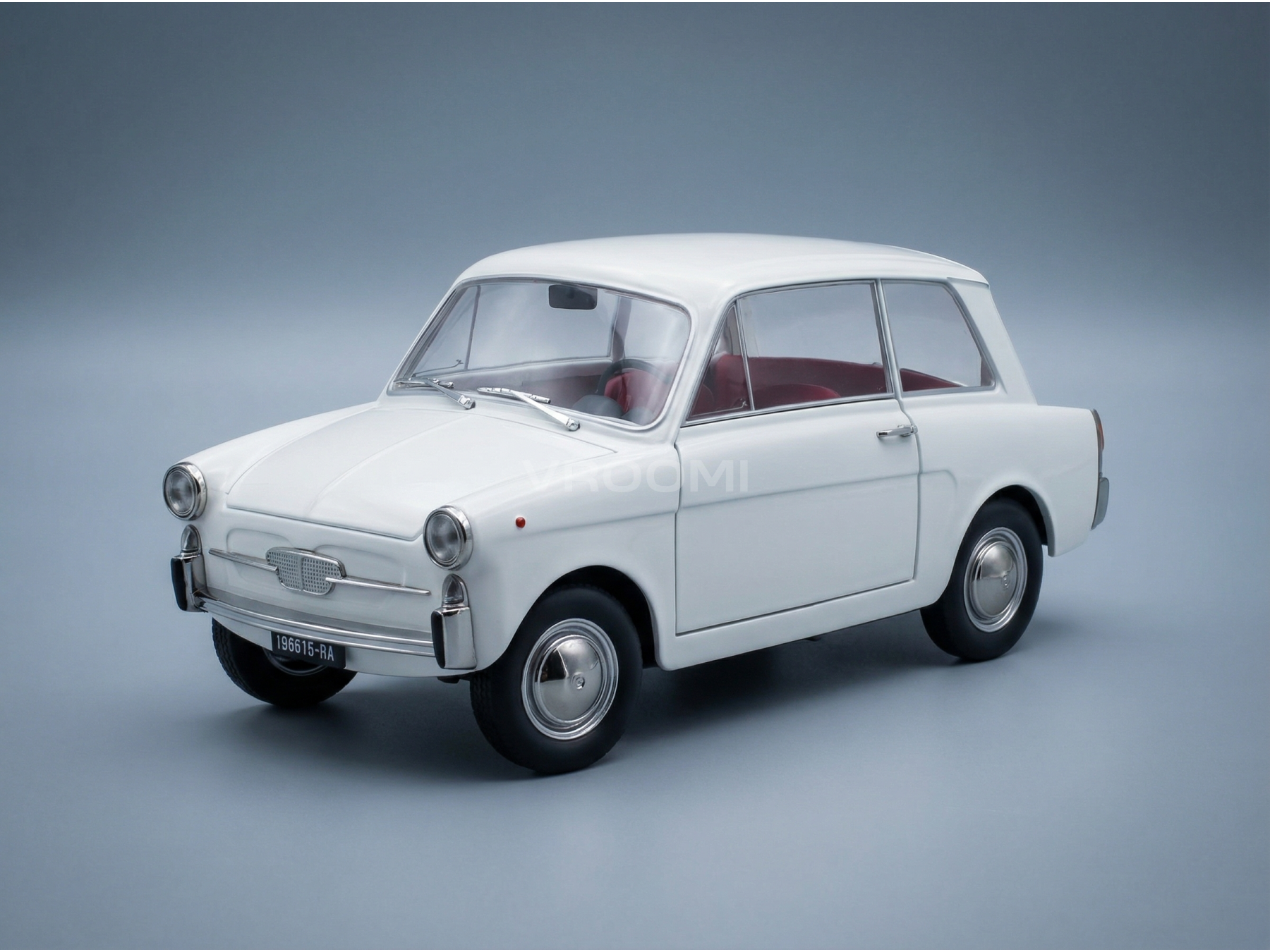 Coche en miniatura vintage de color blanco con interior rojo, presentado por Vroomi para coleccionistas