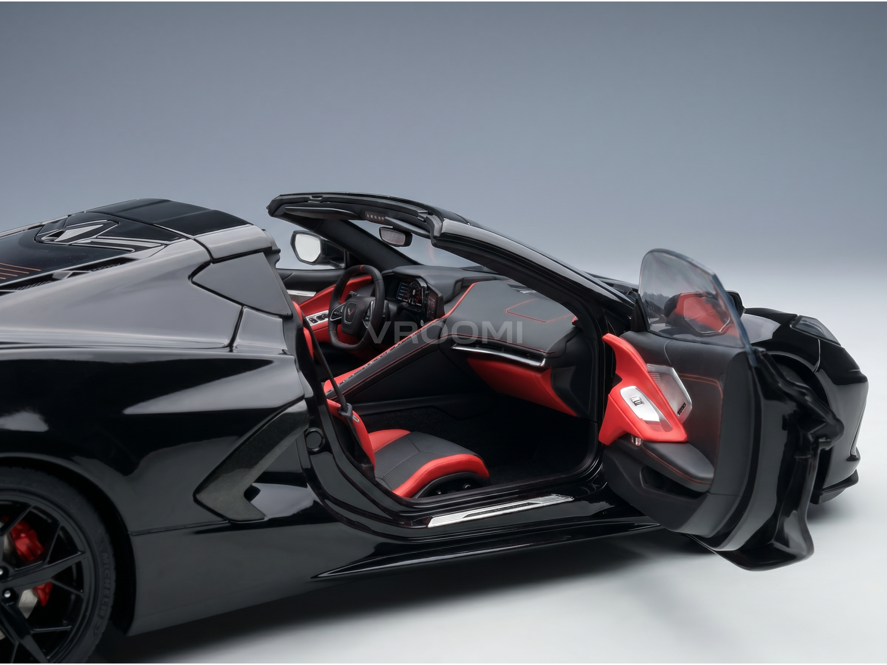 Zwart schaalmodel van een auto met rood interieur en open deuren, gepresenteerd door Vroomi voor verzamelaars.