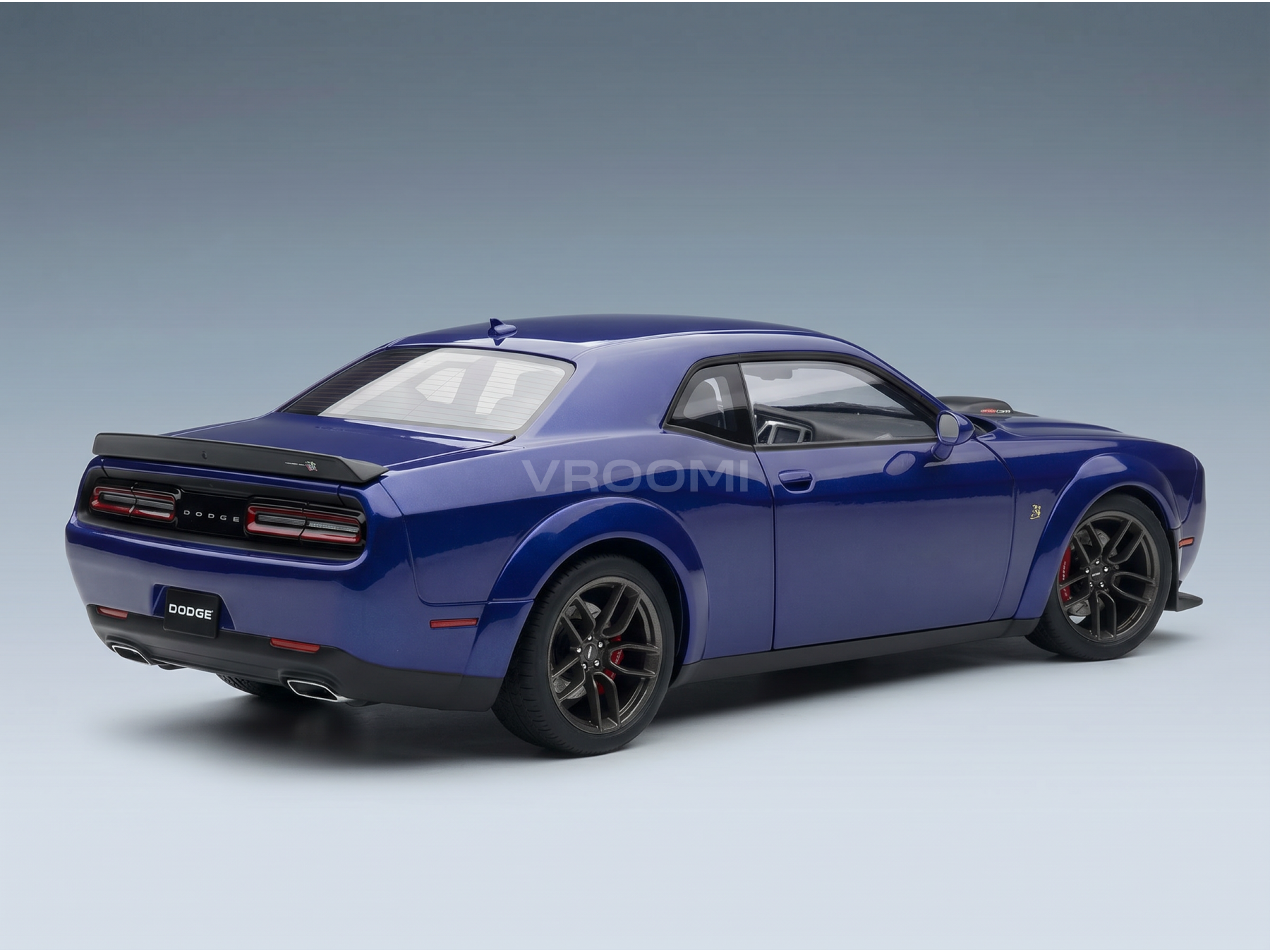Maquette de voiture Dodge Challenger bleue de la marque Vroomi, avec jantes noires et aileron arrière, sur fond dégradé