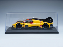 Maqueta a escala de un Ferrari 499P amarillo en vitrina, con los logotipos de Richard Mille y Michelin, ideal para los coleccionistas de Vroomi.