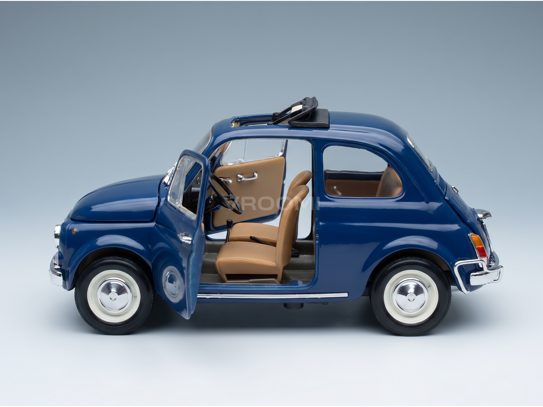 Modèle réduit de voiture classique bleu avec porte ouverte, intérieur beige et pneus à flancs blancs — Vroomi