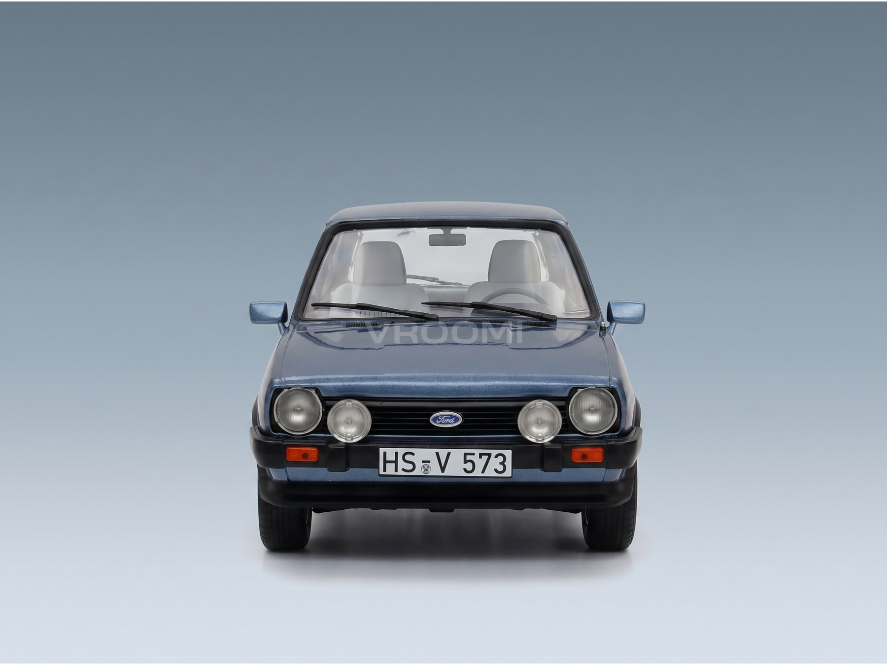 Maquette de voiture Ford Escort Mk3 bleue de la marque Vroomi, avec une calandre, des phares et une plaque d'immatriculation « HS-V 573 » très détaillés.
