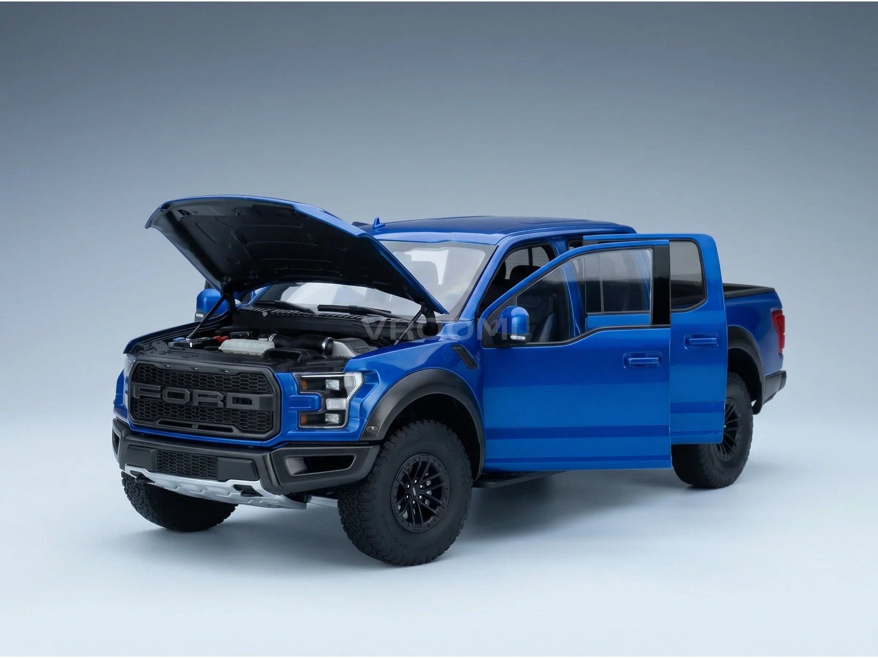 Maqueta a escala de un Ford Raptor azul con el capó y las puertas abiertos y un motor detallado, en Vroomi