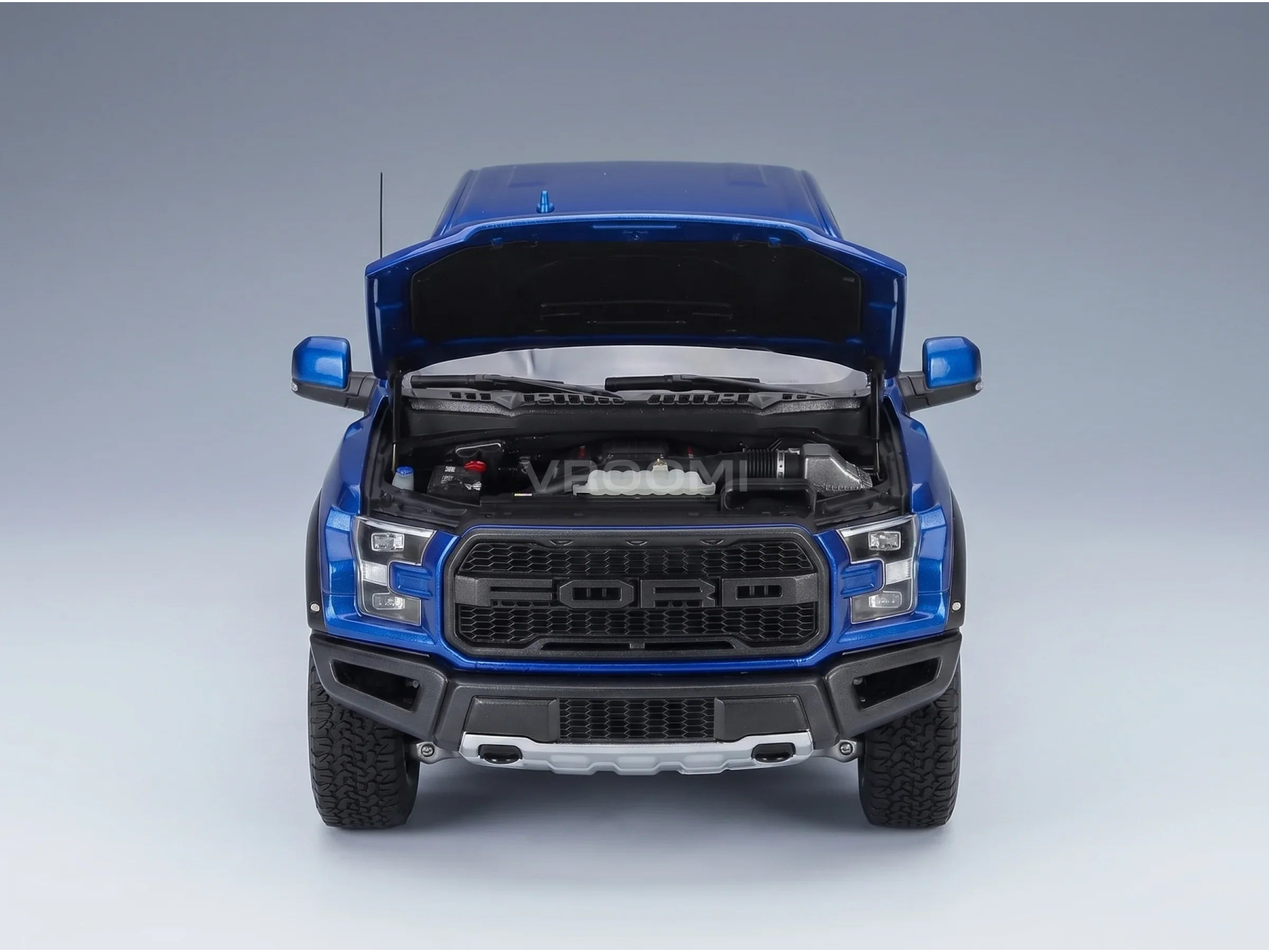 Maqueta a escala de un Ford Raptor azul con el capó abierto y motor detallado, de Vroomi