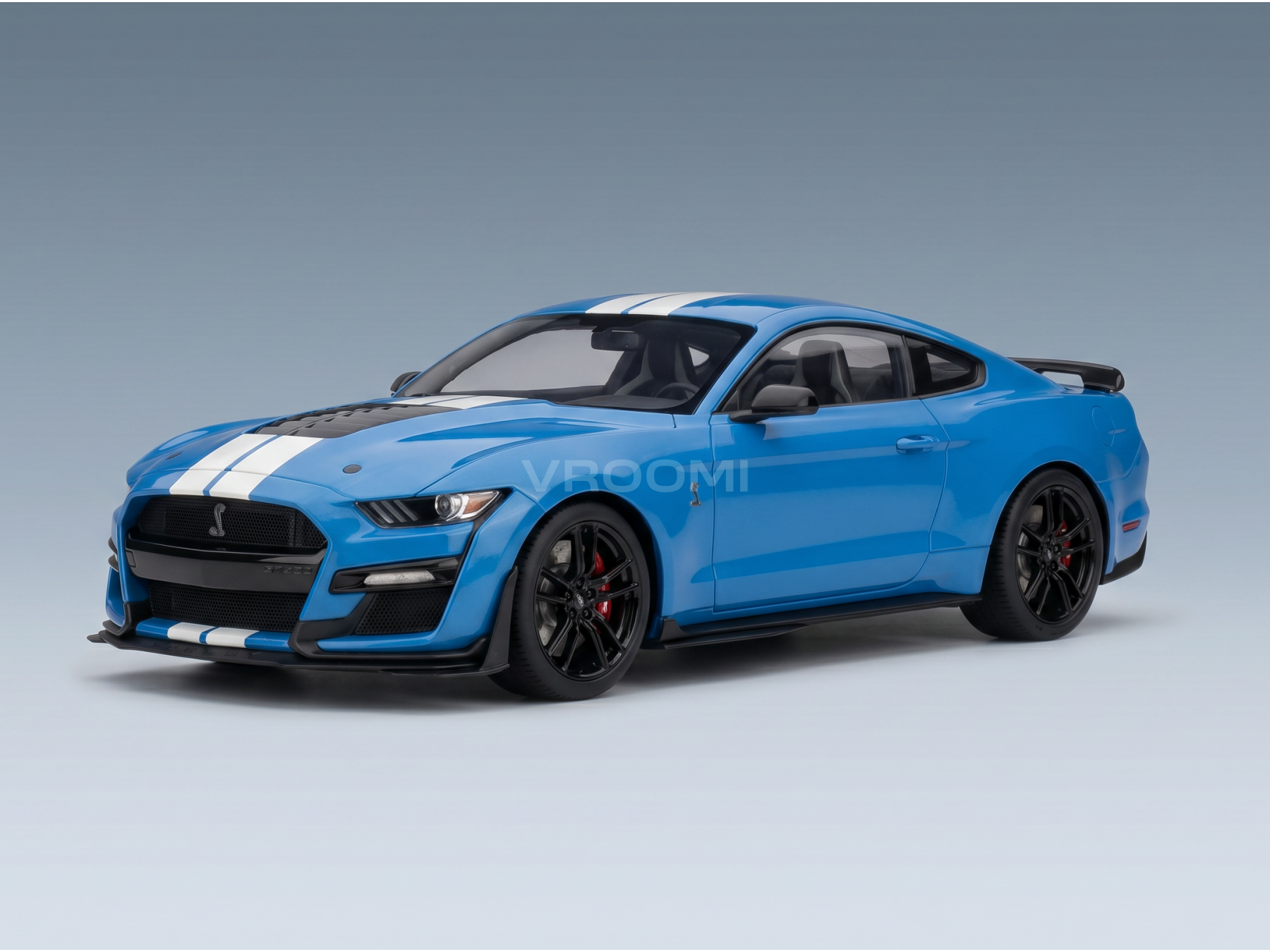 Maqueta a escala de un Ford Mustang Shelby GT500 azul con franjas blancas de competición, llantas negras y el logotipo de Vroomi