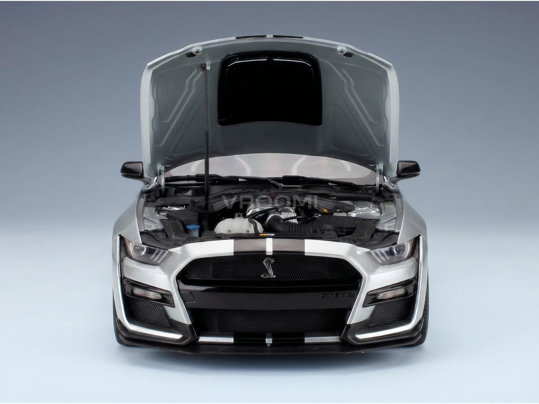 Maqueta a escala del Shelby GT500 plateado con el capó abierto, motor detallado y la marca de agua «Vroomi»