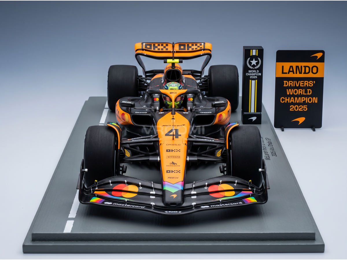 Miniature de la McLaren F1 MCL39 orange et noire avec détails arc-en-ciel sur l'aileron avant, GP d'Abu Dhabi 2025 avec panneau de stands