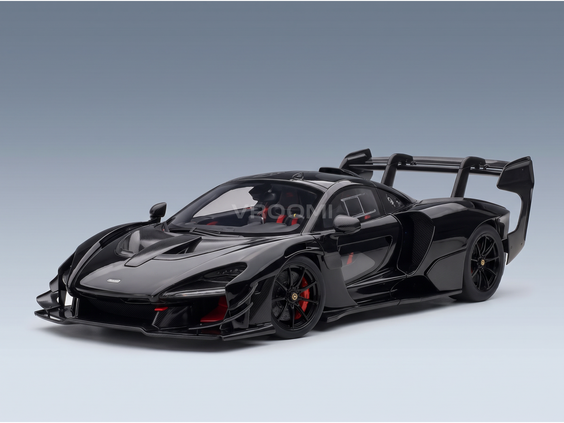 Black McLaren Senna scale model car with carbon fiber details and red accents, showcased by Vroomi