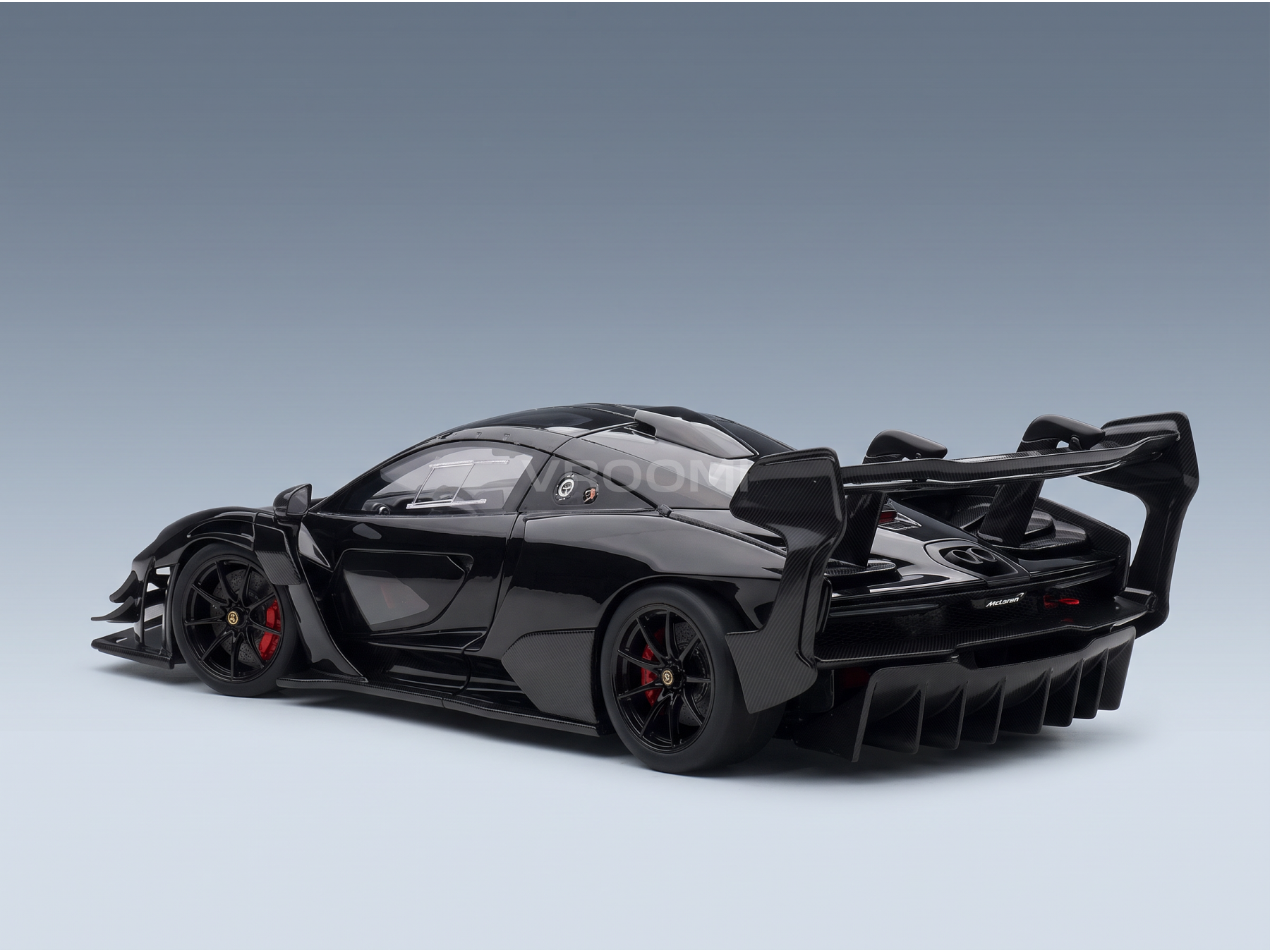 Black McLaren Senna scale model car with carbon fiber details, red brake calipers, and rear wing — Vroomi