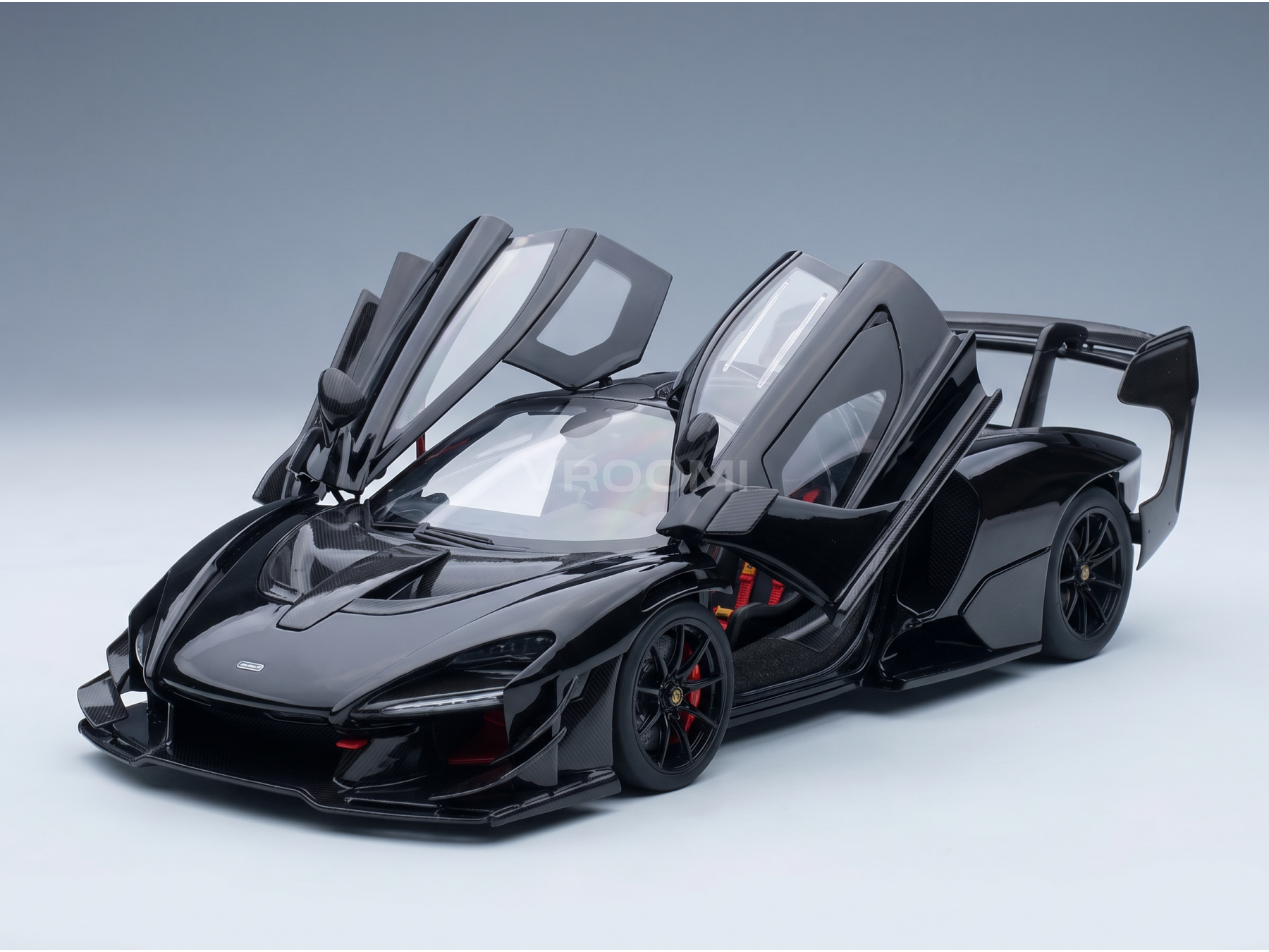Black McLaren Senna scale model car with open doors, carbon fiber details, red accents — Vroomi