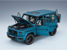 Maqueta de un Mercedes-AMG G63 de color verde azulado con las puertas y el capó abiertos, presentada por Vroomi