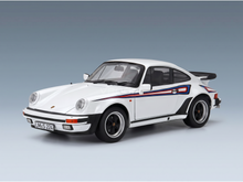 Maqueta a escala de un Porsche 911 blanco con rayas rojas y azules, con llantas negras y alerón trasero, de Vroomi