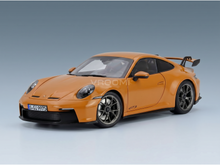 Maqueta a escala de un Porsche 911 GT3 naranja con el emblema GT3, llantas negras y alerón trasero, expuesta en Vroomi