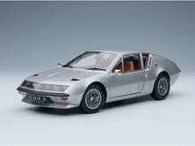 Silver scale model car with tan interior, detailed wheels and license plate, showcased by Vroomi