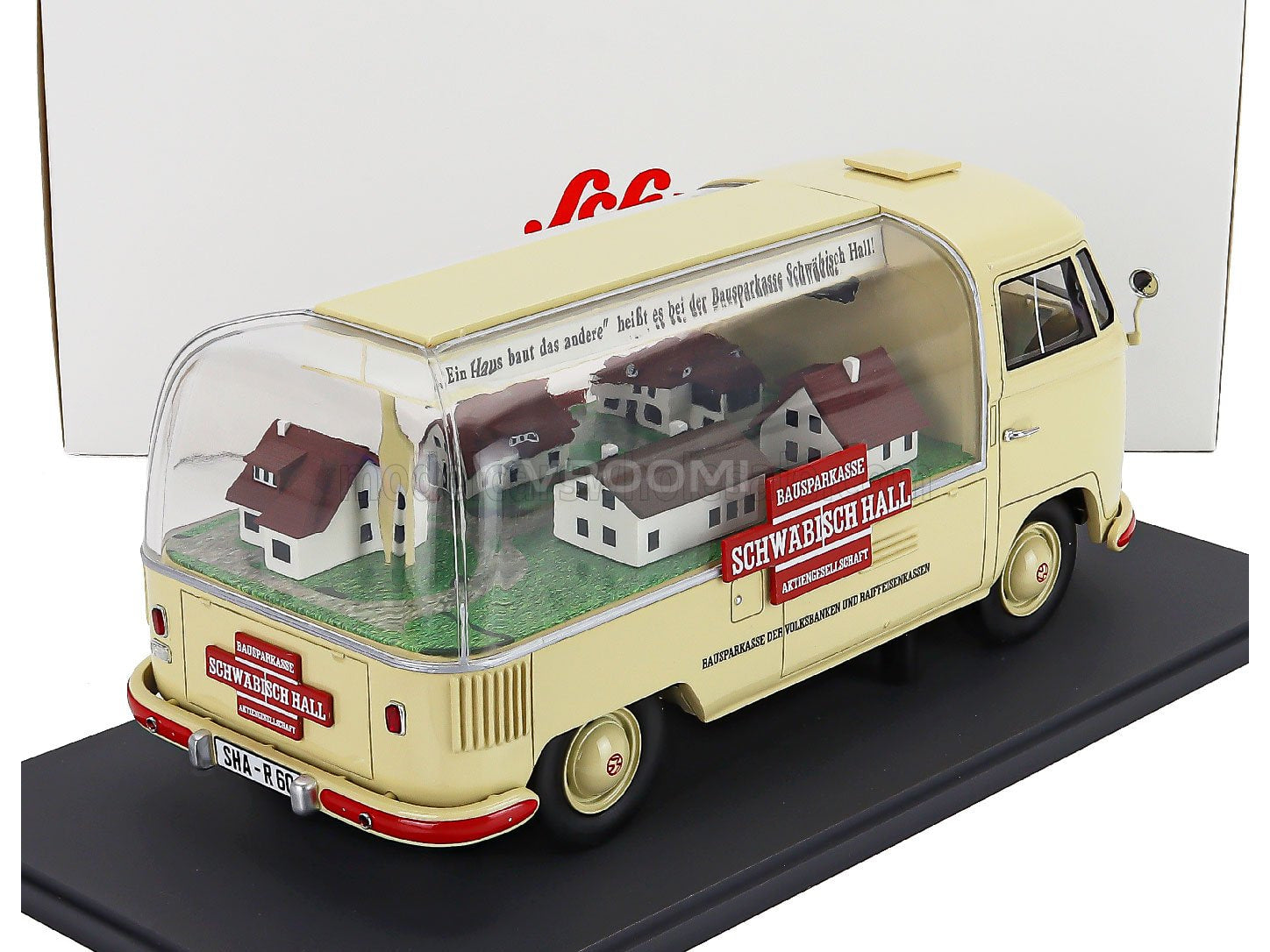 Cream VW bus scale model car with miniature houses inside, displayed on black base. Vroomi