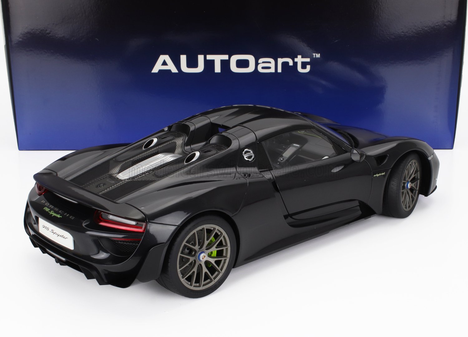 Modelo de coche Porsche 918 Spyder negro con detalles de fibra de carbono sobre fondo AUTOart, disponible en Vroomi.