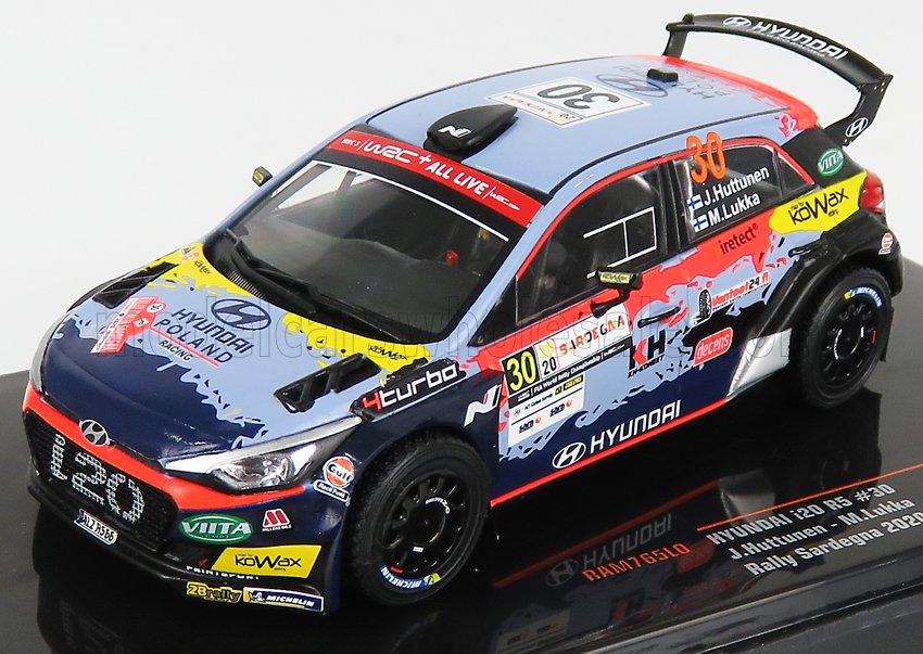 Modelo de coche de rally Hyundai R5 con colores azul, rojo y amarillo, patrocinado por Hyundai y otros, presentado en una base de exposición y ahora disponible a través de Vroomi.