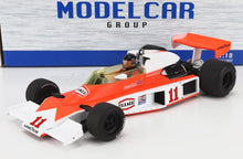 Coche de carreras McLaren M23 de Fórmula 1 a escala 1/18, fabricado en metal fundido, en color naranja y blanco, con neumáticos Goodyear y la pegatina de James Hunt, disponible en Vroomi.