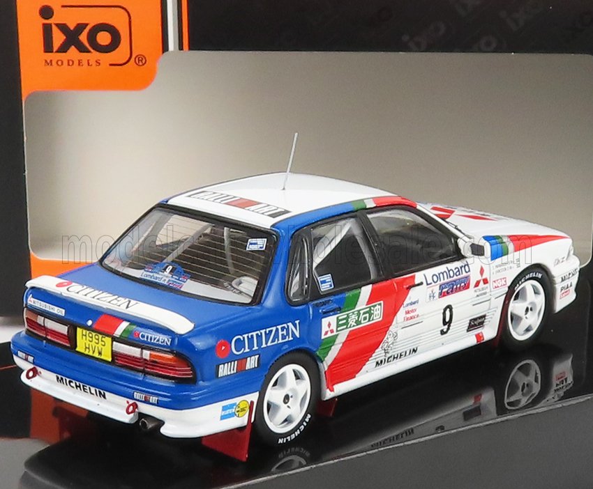 IXO Models Mitsubishi Lancer rally car model in blue, white, and red livery with sponsor decals, offered via Vroomi