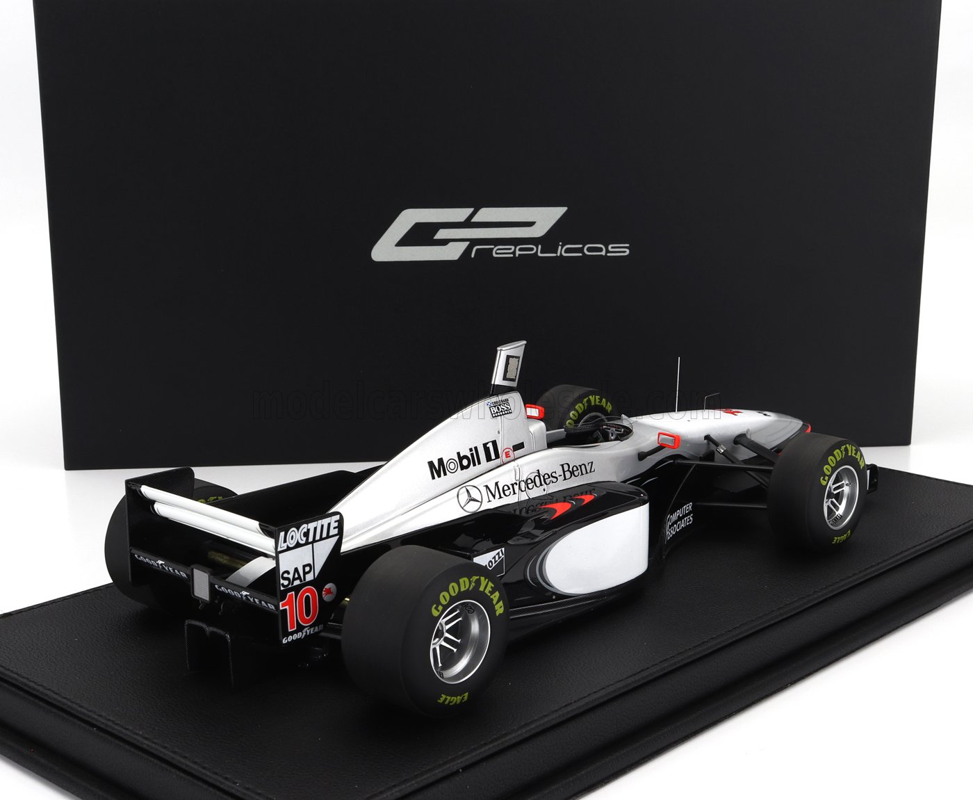 Modelo de coche de Fórmula 1 McLaren MP4/8 con los logotipos de Mobil 1 y Mercedes-Benz, expuesto sobre una base negra, vendido en Vroomi.