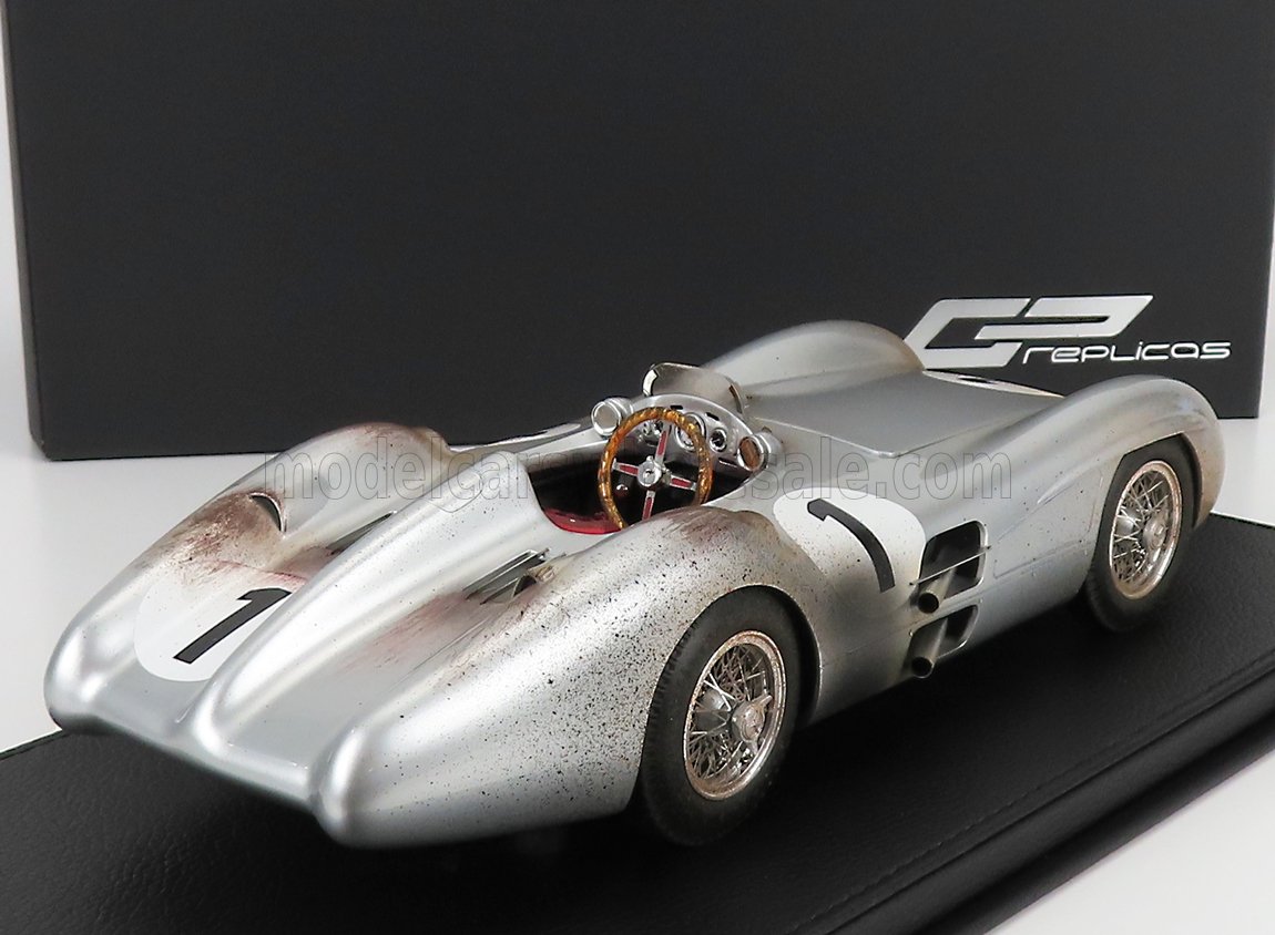 Silver vintage racing car model with weathered details and wooden steering wheel on display, offered on Vroomi