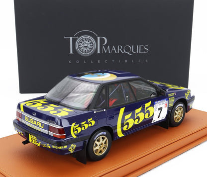 Modelo de coche de rally Subaru Legacy a escala 1:18 con decoración 555 sobre base de cuero, presentado por Top Marques, disponible en Vroomi.