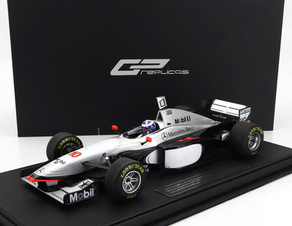 1:18 scale McLaren MP4/12 Formula 1 model car in silver and black with Mobil and Mercedes-Benz branding, shown on display base, now offered on Vroomi