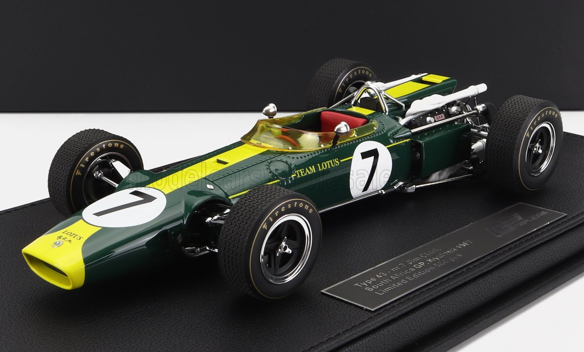 Modelo detallado de un coche de carreras Team Lotus Type 43 verde y amarillo con el número 7, expuesto en un soporte de exhibición, ahora disponible en Vroomi.
