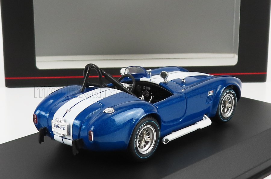 Modelo de coche Shelby Cobra 427 SC azul con rayas blancas de carreras expuesto en un soporte negro, disponible a través de Vroomi.