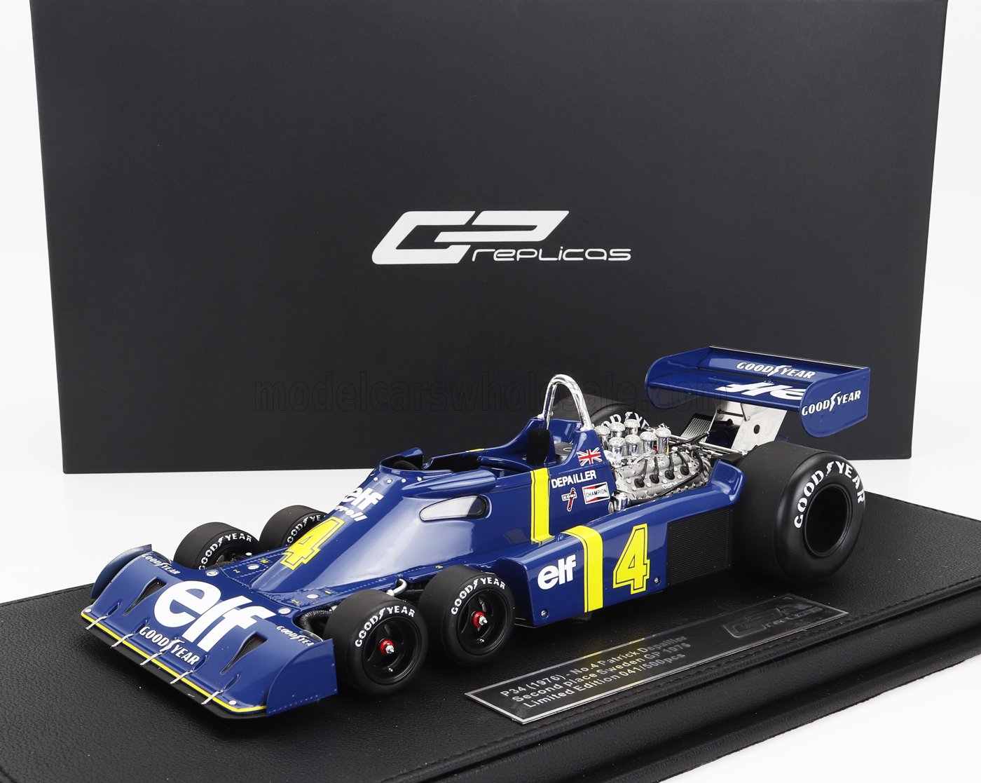 Modelo de coche de F1 Tyrrell P34 azul de seis ruedas con el número 4 amarillo y el logotipo de Elf, expuesto sobre una base negra con la marca GP Replicas, ahora disponible en Vroomi.
