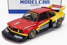 Modelo de coche de carreras Rodenstock BMW a escala 1/18 en rojo, amarillo y negro con adhesivos de patrocinadores, disponible en Vroomi.