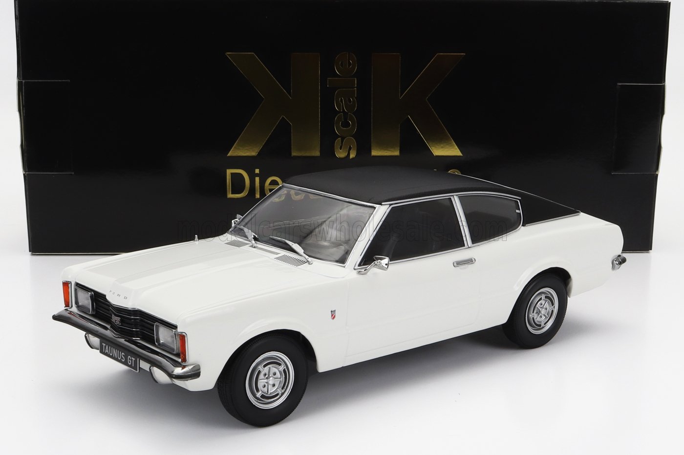 Coche modelo Ford Taunus GT blanco con techo negro delante de una caja Scale K negra y dorada, disponible en Vroomi.