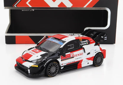 Maqueta a escala de un coche de rally Toyota con colores rojo, blanco y negro, en caja, disponible en Vroomi.