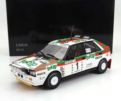 Modelo de coche de rally Lancia Delta con los colores de Totip Racing, expuesto con una caja negra Lancia Delta, disponible en Vroomi.