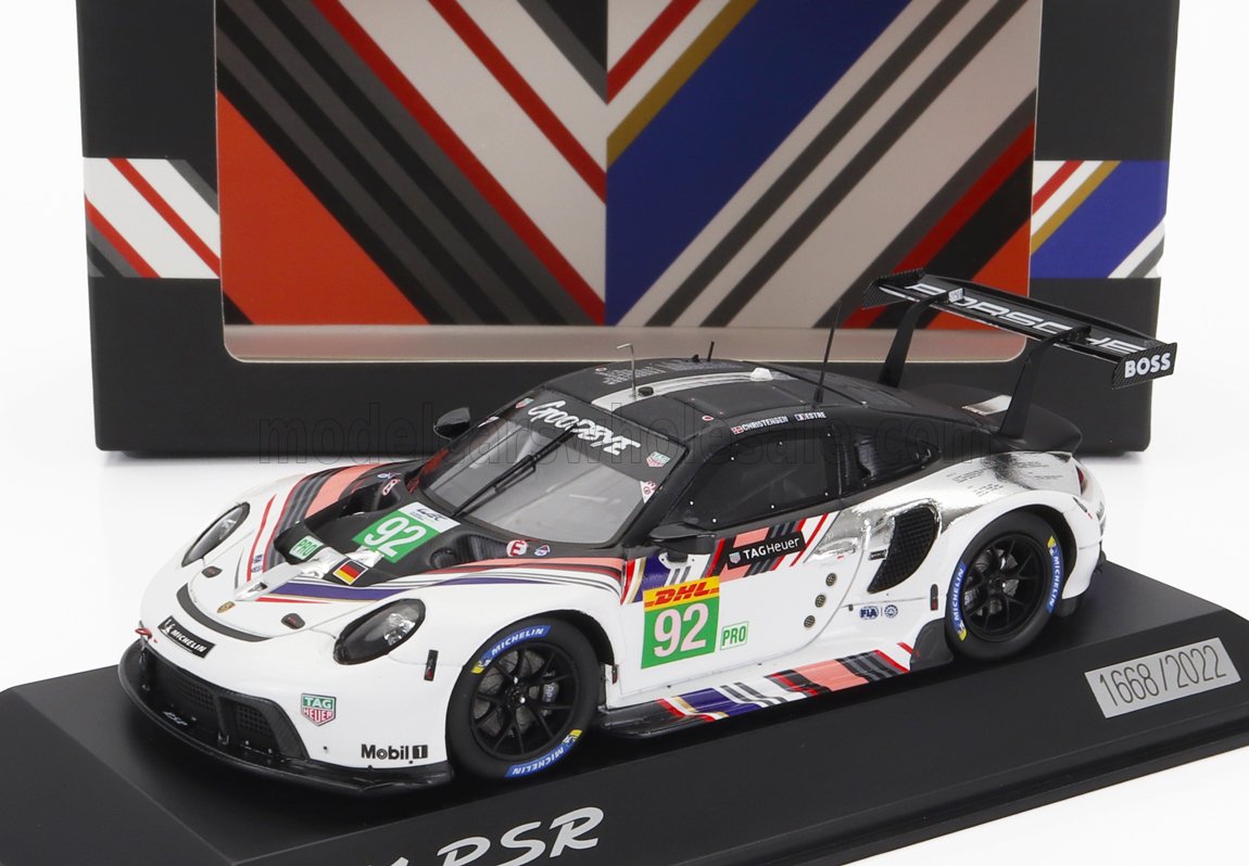 Modelo de coche de carreras Porsche 911 RSR blanco con el número 92 y adhesivos de patrocinadores, expuesto en un soporte, disponible en Vroomi.