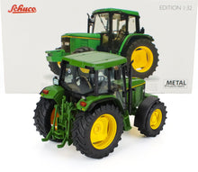 Modelo de tractor Schuco a escala 1:32, fabricado en metal fundido, de color verde y amarillo, con neumáticos detallados y piezas de metal y plástico, disponible en Vroomi.