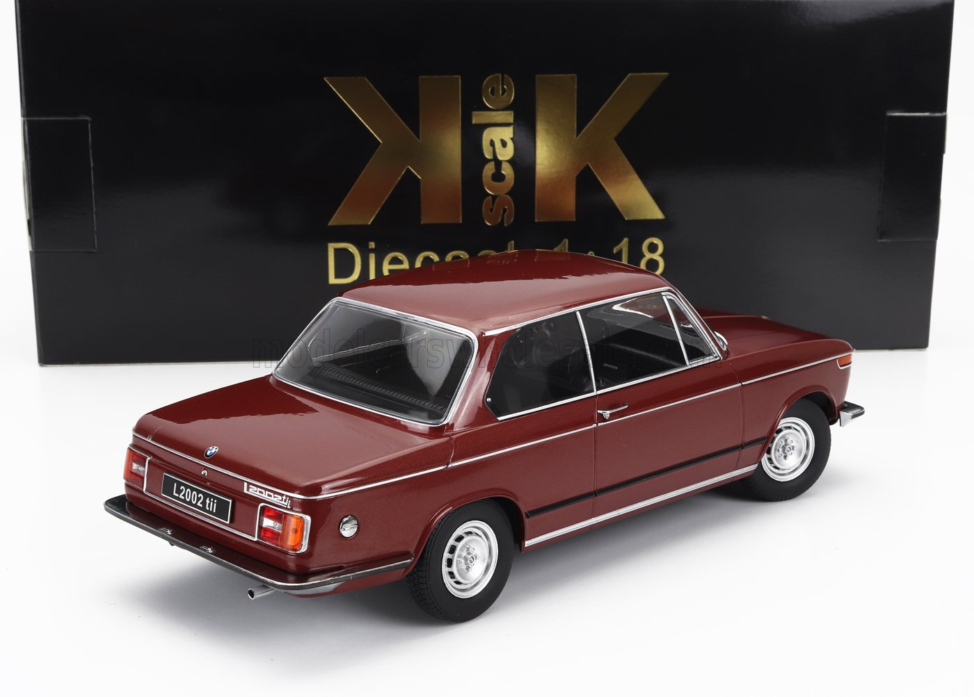 Coche en miniatura BMW 2002 tii de color granate con detalles cromados, expuesto delante de una caja negra KK Scale 1:18, disponible en Vroomi.