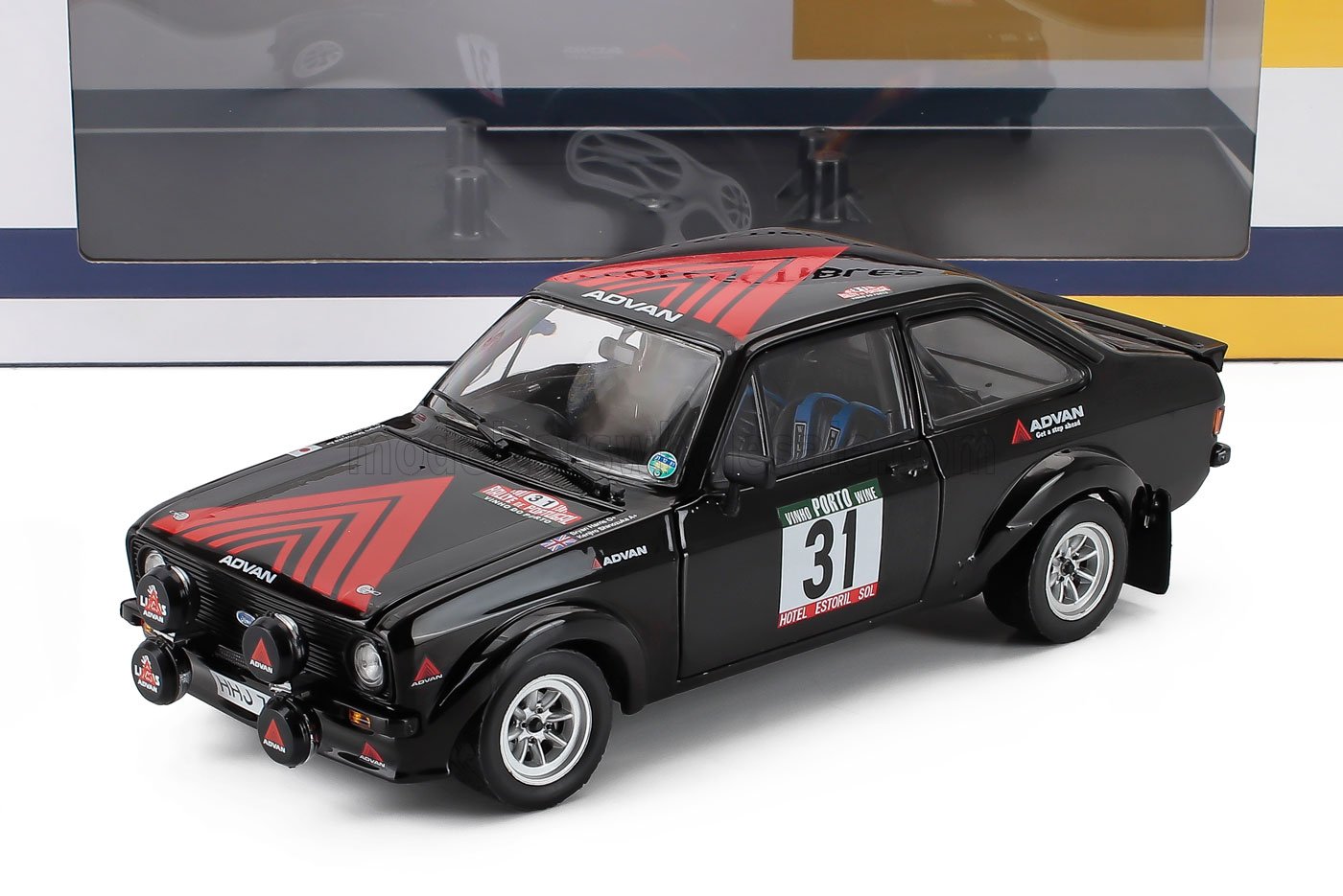Modelo a escala 1/18 del coche de rally Ford Escort con decoración roja y negra, disponible en Vroomi.