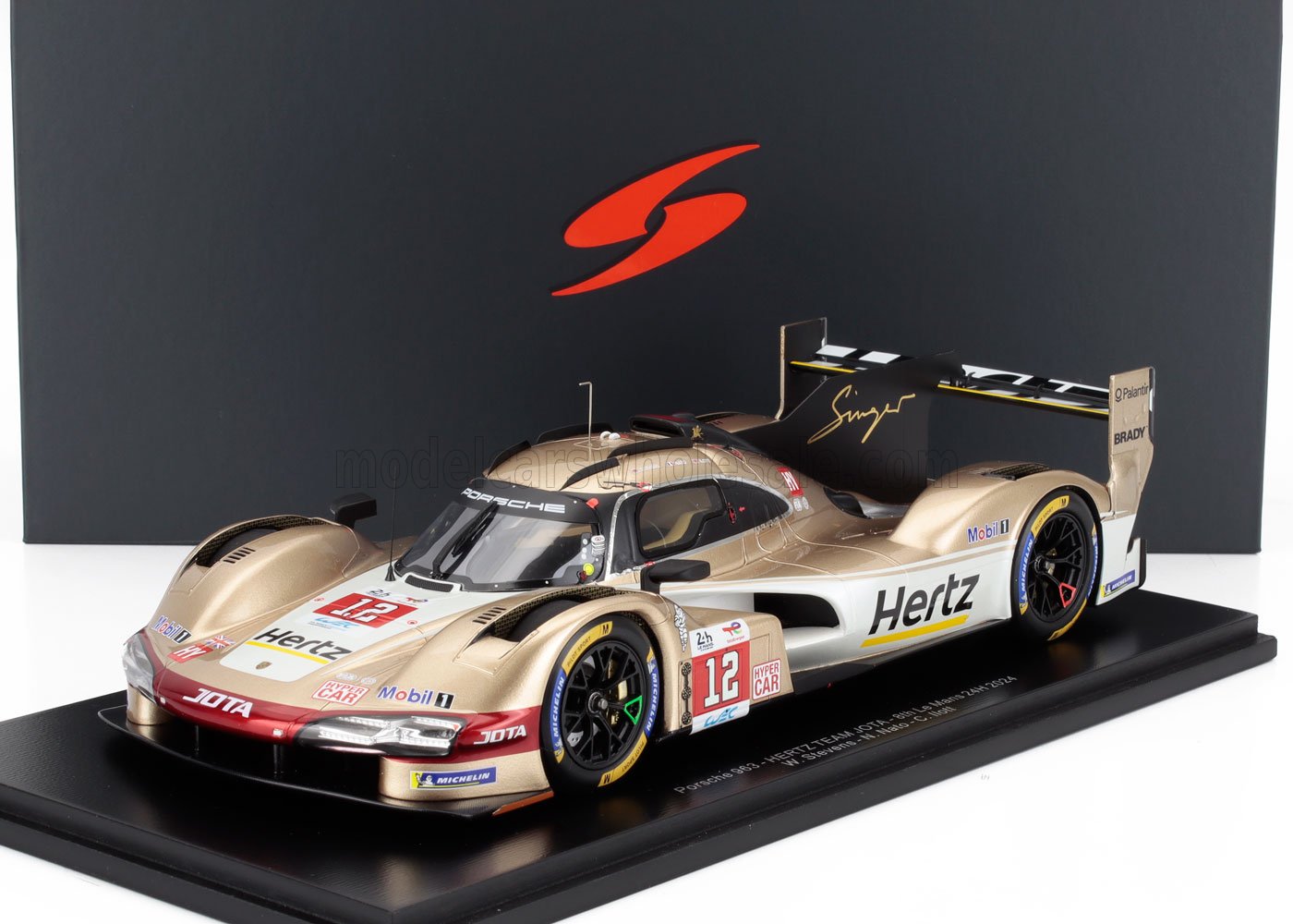 Modelo de coche de carreras Porsche 963 dorado y blanco con la marca Hertz, expuesto en un soporte, disponible en Vroomi.