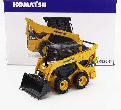 Maqueta a escala de la minicargadora Komatsu SK820 amarilla y negra con cuchara detallada, presentada en su caja con la marca, disponible en Vroomi.