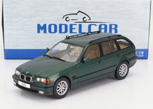 Coche en miniatura BMW 325i familiar verde a escala 1:18 con interior detallado, mostrado delante de la caja del coche en miniatura, disponible en Vroomi.